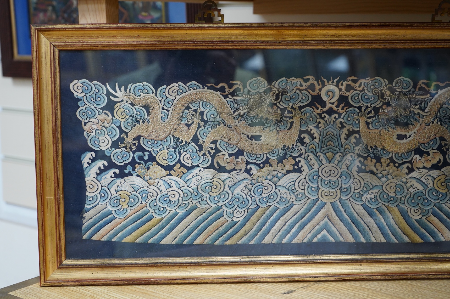 A framed late 19th / early 20th century Chinese silk embroidered five claw dragon panel from the base of a robe, 59cm wide x 23cm high. Condition - good, colours and embroidery strong